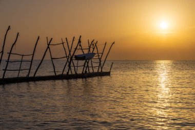 Savudrija teknelerinin asılması geleneksel tahta vinçlerde gün batımında sallanıyor.