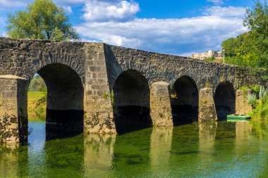 The old stone bridge on the Dobra River, with a Novigrad Castle in the background, Croatia