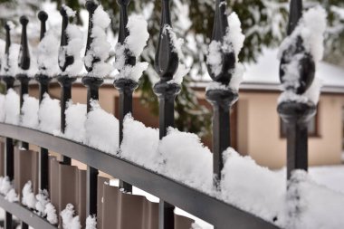 Soğuk bir kış gününde kar altında metal çitler..