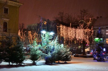 Soğuk bir kış gecesinde sokak lambalarıyla aydınlatılan kış süslemeleri ve sokaklarda kar. Gece. 