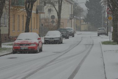 Karla kaplı yollar, karda tekerlek izleri ve yoğun kar yağışı sırasında karla kaplı arabalar. Gün. 