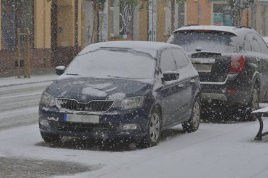 Karla kaplı yollar, karda tekerlek izleri ve yoğun kar yağışı sırasında karla kaplı arabalar. Gün. 