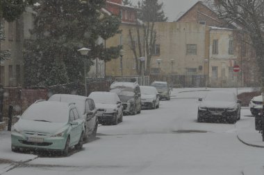 Karla kaplı yollar, karda tekerlek izleri ve yoğun kar yağışı sırasında karla kaplı arabalar. Gün. 