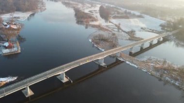 Güneşli bir kış gününde şehrin, nehrin ve köprülerin üzerinde insansız hava aracı uçuşu.