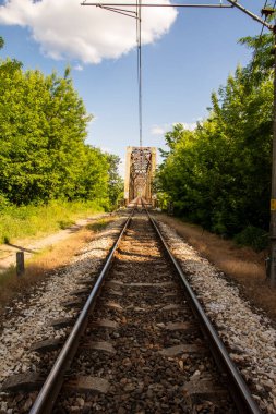 Demiryolunun metal yapısı nehrin üzerinde bulutlu mavi bir gökyüzünün arka planına karşı. Gün. 