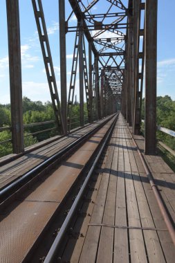 Demiryolunun metal yapısı nehrin üzerinde bulutlu mavi bir gökyüzünün arka planına karşı. Gün. 