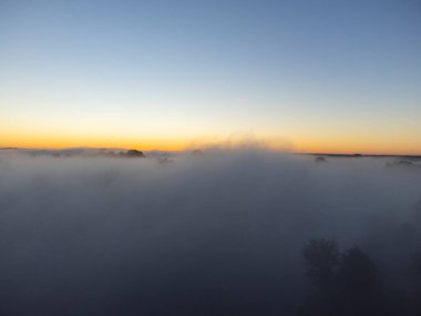 Sis üzerinde insansız hava aracının resimleri. Nehir, orman, tarlalar ve çayırlar sisli bir yaz şafağında.