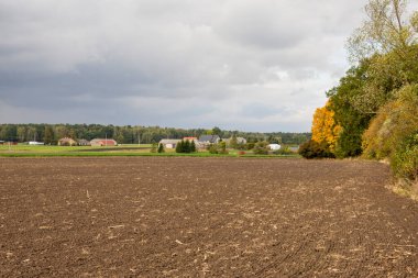 Tarlanın üzerindeki kara bulutlar ve arka plandaki köy.. 