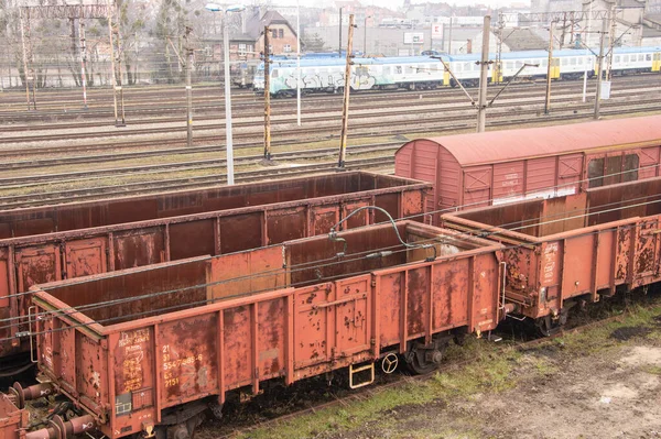 Railway carriages, railway infrastructure, tracks, rails and power cables over the tracks.