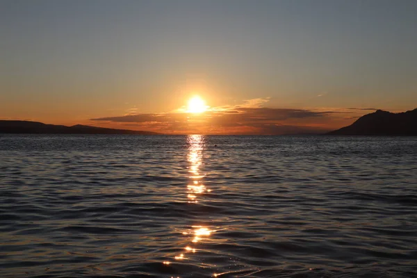 Deniz kenarında gün batımı, batan güneşin ışınlarında resimli bulutlar. Gün batımında deniz manzarası, ufukta turuncu güneş bir yaz akşamı bulutları ve denizi aydınlatıyor.