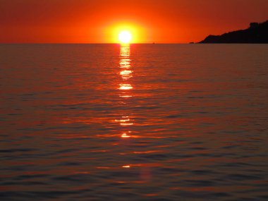 Denizin üzerinde parlak gün batımı. Ufuktaki güneş, suyun yüzeyine yansıyor. Gün batımında deniz manzarası, deniz ve gökyüzü kırmızı-turuncu. Karadeniz 'de dinlen. Manzara, manzara, akşam denizi manzarası..