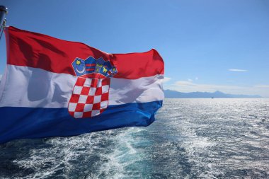 Denizin arka planında, deniz kıyısında ve açık gökyüzünde Hırvatistan bayrağı