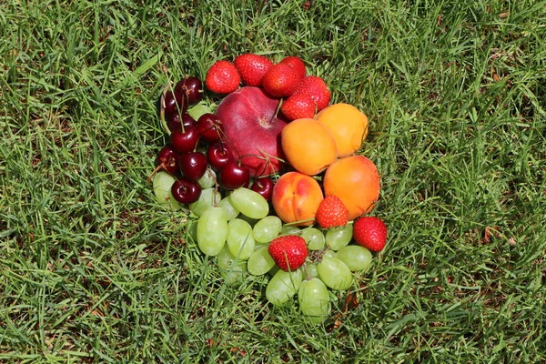 Fruit in the grass.Ripe peaches, cherries, strawberries, apricots and grapes on a green background