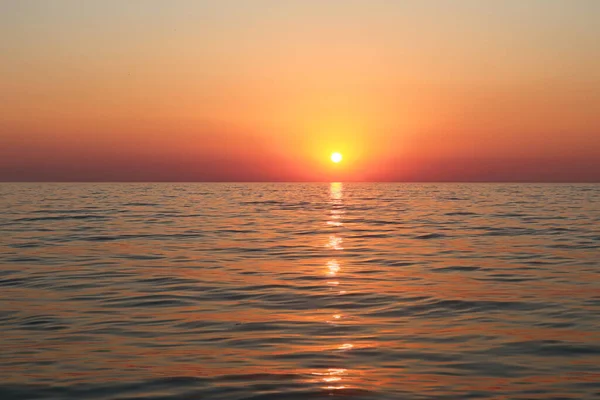 Picturesque orange sunset on the sea coast of Italy, Calabria. Sunset on the sea, orange sky and sea, sun reflection on the surface