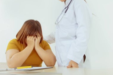 Tıbbi bakım konsepti: Genç Asyalı obez kadınlar hastalıklarından dolayı depresyonda ve endişeliyken, kadın doktor olumlu bir omuza geçer ve onları hastalığı tedavi etmeye teşvik eder.