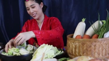 Kırmızı chuk hanbok giyen güzel Asyalı kadın elleri bir kasede tuz ve sebze haşlıyor. Geleneksel Kore kimchi 'si havuç, turp gibi taze baharatlarla pişirilir..