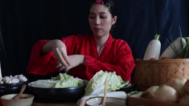 赤韓服を着たアジアの女性は 伝統的な韓国料理であるキムチを白いキャベツのボウルに塩を振りかけ きれいで新鮮な野菜で丁寧に練り上げています — ストック動画