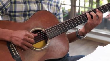 Akustik gitar çalan ve müzik besteleyen müzisyenlerin yakın çekimi eğlence için müzik yaratıyor..