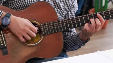 Online bir sınıfta akustik gitar çalan klasik gitar öğretmeninin elleri..