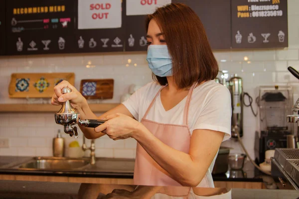 İş kadını, Asyalı barista maske takıyor, bir liman filtresi tutuyor kahve filtresi öğütülmüş kahve çekirdekleri müşterilere en iyi ve lezzetli kahveyi hazırlamak için: Seçici Odaklanma