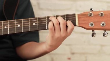 Evde akustik gitar çalan genç adamın ellerini yakın plan çek..