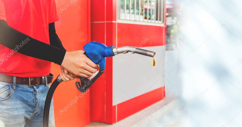 Gas station worker stands holding fuel injectors serving customers while refueling at a quality gas station : Panoramic banner