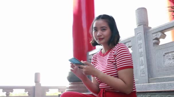 Nette Asiatin Teenageralter Leuchtend Roter Kleidung Sitzt Interessiert Auf Ihrem — Stockvideo