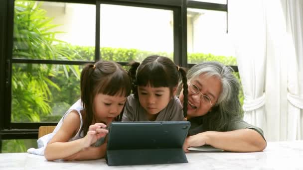 Бабуся Допомагає Своїм Двом Азіатським Онукам Навчатися Онлайн Роблячи Домашнє — стокове відео