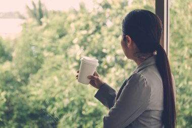 Konseptler tek başına duruyor: İş kadını aynaya hayranlıkla bakıyor, ofisteki pencereden dışarı bakıyor. Yumuşak odak