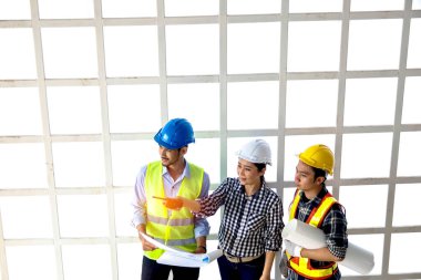 Üst düzey ekip çalışması ve saha çalışması önde gelen ve yetenekli bayan mimarlar inşaat projesini işaret ediyor ve erkek işçilere dikkatlice açıklıyorlar..