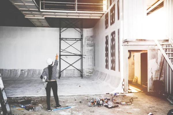 The female architect examined the field work, working on an incomplete construction site and pointing to the point where the top path must be corrected for safety.