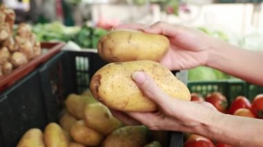 Bir kadının elinin yakın çekimi marketten taze patates alıp akşam yemeği pişirmek ya da aile yemeği hazırlamak için..