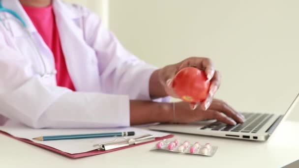 非洲裔美国女营养师坐在键盘上打字 记录有关西红柿的信息 以及西红柿对病人饮食计划的益处 从而为诊所的工作节省笔记本电脑 — 图库视频影像