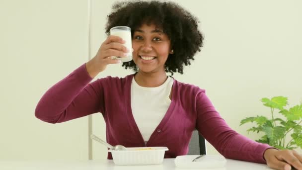 午餐时 非洲裔美国女人坐在餐桌旁 吃一盒盒饭 并选择喝牛奶来增加风味 — 图库视频影像