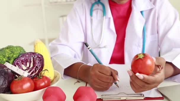 Profesjonalny Lekarz Żywienia Afroamerykańska Dietetyczka Siada Notatki Korzyści Pomidorów Brokułów — Wideo stockowe