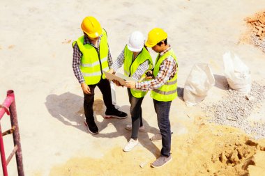 Üst düzey ekip mühendisleri kadın mimar ustabaşının iki erkek işçiye açıklamak ve inşaat ve yenileme çalışmalarını plana göre bölmek için dizüstü bilgisayar kullanmasını sağladı..