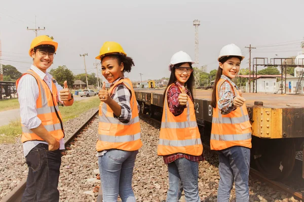 Team professional engineers from various nationalities with Japanese male technicians and Korean female colleagues Thai and African American women show thumbs up during diesel rail maintenance.