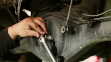 Araç bakım merkezindeki tamirci, arka diferansiyel kilit fındığını sıkılaştırmak için bir anahtar kullanıyor.