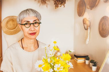 Portre profili güzel, 60 yaşında Asyalı kısa gri saçlı, gözlüklü, sağlıklı, parlak yüzlü, neşeli, mutlu, gülümseyen, kameraya bakan bir kadın..