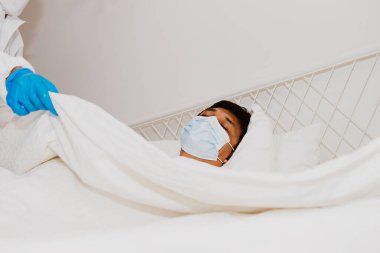 Doktor yaşlı hastaların uyuması için PPE giysi battaniyesi giyiyor: Yaşlı Asya 'lı enfeksiyon kapmış erkek hasta enfeksiyonunu önlemek ve hastanın güvenli bölgesini izole etmek için hastaneye kaldırılıyor.