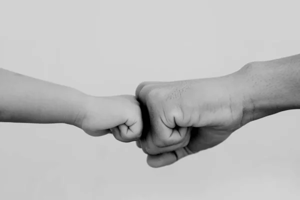 Black and white pictures father\'s big fist and son\'s little hand collide with each other, strength training and early childhood learning teaching.