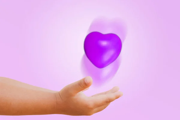 Little boy waving beautiful purple heart showing love and understanding Infidelity, forbidden uncertainty, hidden barriers and short term relationships : Meaning of the concept of the heart.