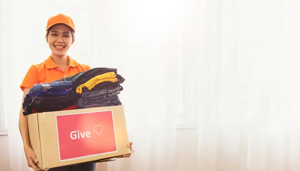 Beautiful kind-hearted asian woman prepares to send used clothes to charity in boxes to the poor migrants war and the homeless : Young woman holding box of clothes donation for charity.