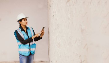 İnşaat alanında beton duvarlar tasarlayan Asyalı kadın mimarlar dizüstü bilgisayar kullanıyor ve seramik ya da ham beton kullanmak istiyor. Müşteriler için karar verme aşamasında..