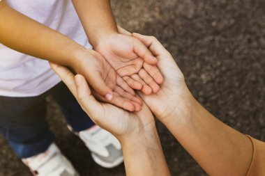 Üst düzey annenin iki eli oğlunun elini tutuyor, oğluna şefkatli ve sevgi dolu bir annelik gösteriyor: dünya aile günü, dünya kalp günü, dünya sağlık günü konsepti.