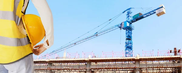 Rear view architect engineer female worker holding safety helmet supervising building construction and field heavy industrial cranes : Select focus : Select focus