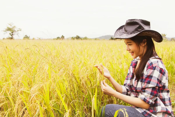 アジアの美しい女性農家のように幸せな収穫の近くで作物が成長しているので 彼女の手の中にある米の黄金の茎を笑顔と誇りで見てください 成功したビジネス女性農家田植え米 — ストック写真
