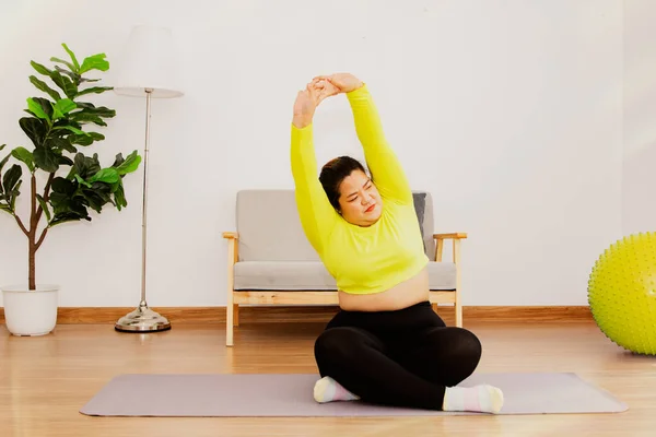 Fat woman exercising at home for health and fitness Exercises to reduce fat sitting and stretch to warm the body to prevent injury before exercise.