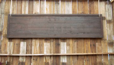 Tahta panellerdeki ahşap duvarda kahverengi bir tahta tabela asılı..