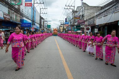 Surat Thani, Tayland 9-11-2022 yaşlı kadınlar geçit töreninde bir rahibin teknesini sürüklemeye yardım ediyorlar. Chak Phra Surat Thani